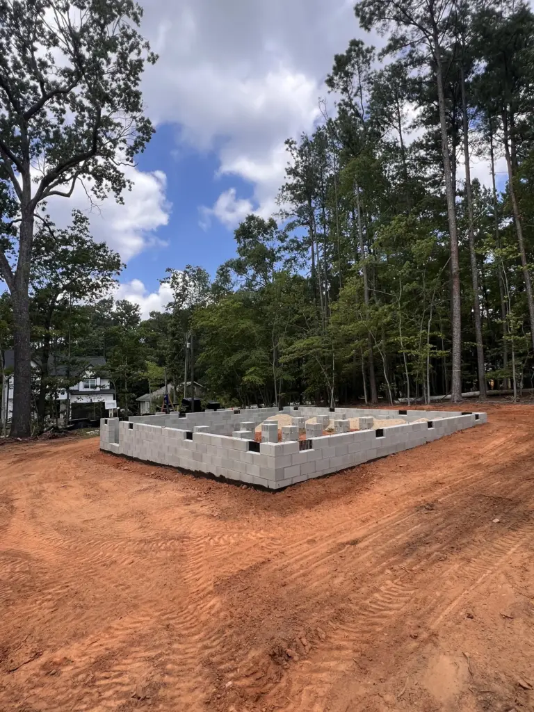 CMU block house foundation on a freshly graded red clay lot surrounded by trees in Gallatin, Tennessee.