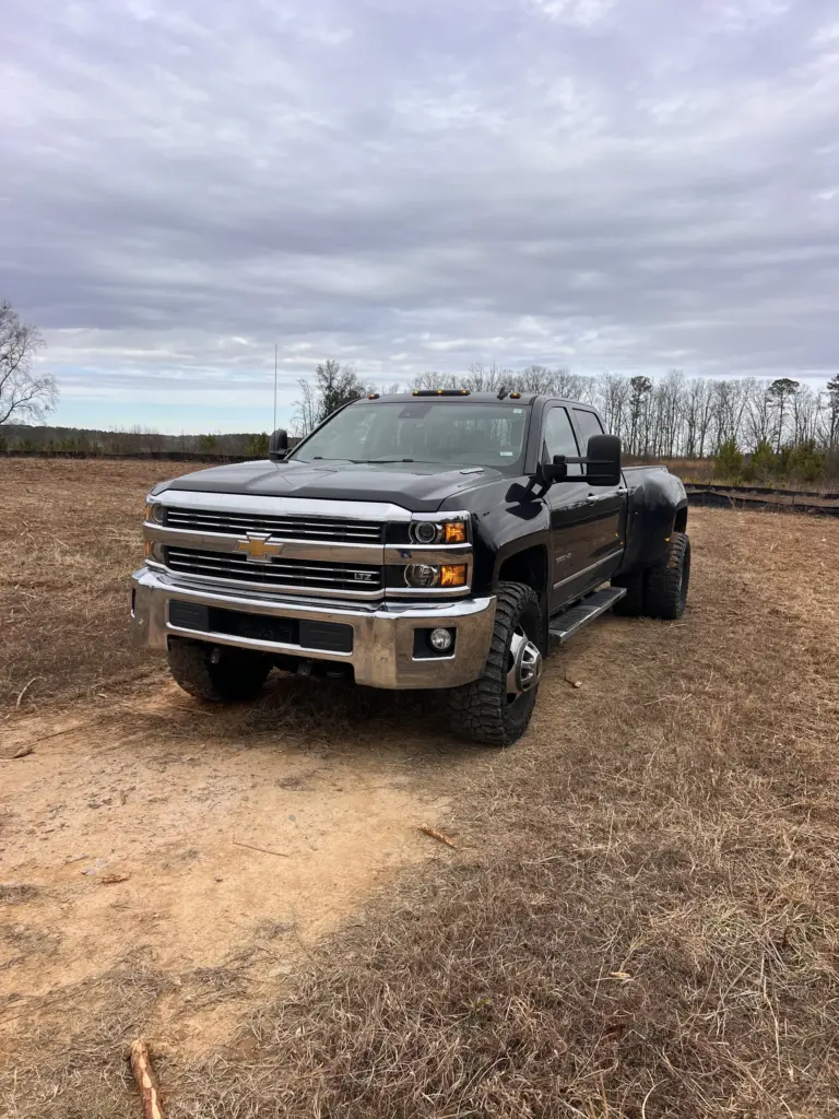 Black dually pickup truck parked on a cleared dirt lot under a cloudy sky in Gallatin, Tennessee.