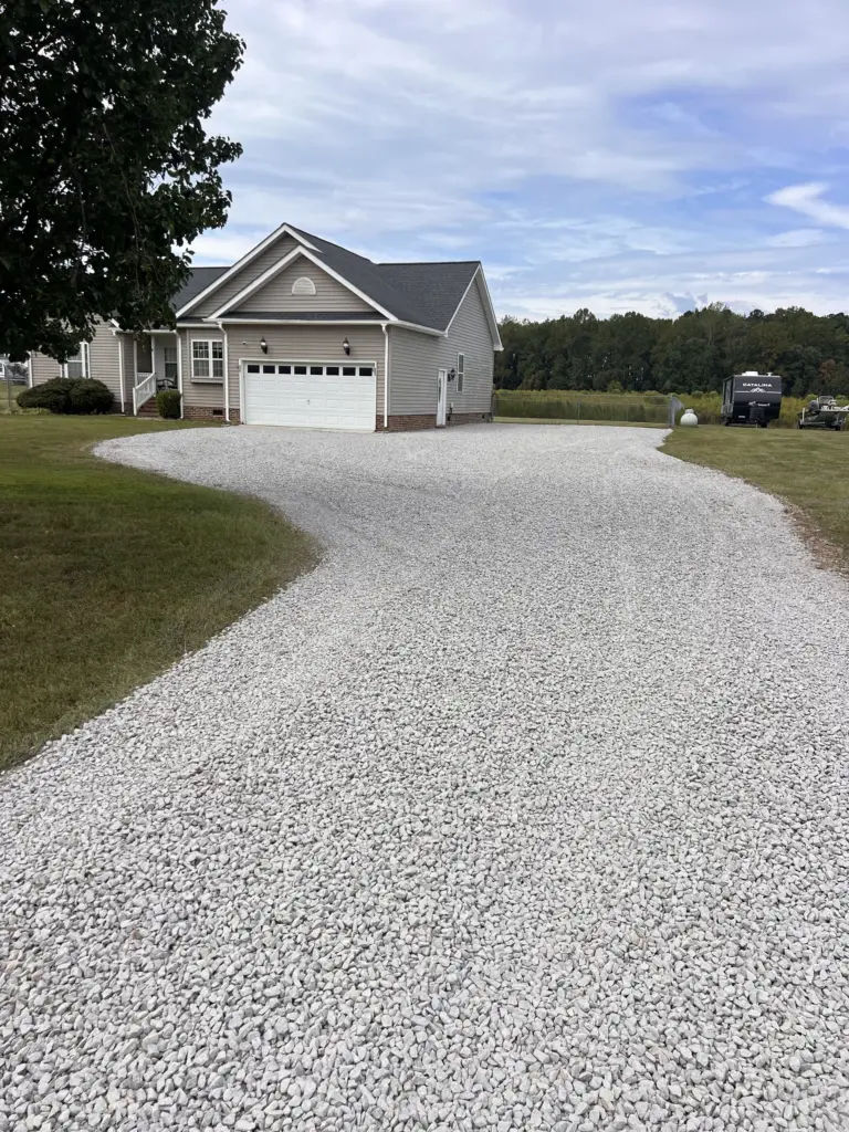 Curved white gravel driveway looping to a two-car garage at a suburban home.