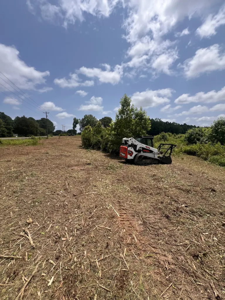 Track loader with brush cutter mulching along a field under power lines in Sumner County, TN.
